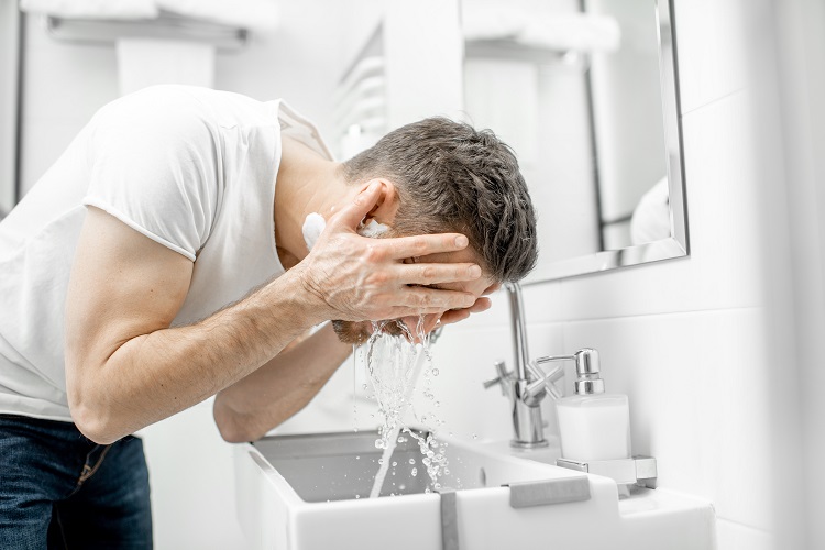 mężczyzna myjący twarz
